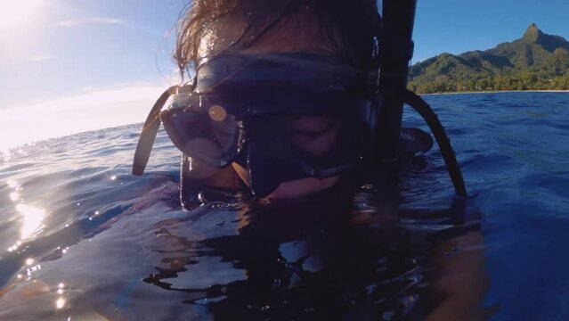 Selfie of Asian female diver wearing diving gear mask and snorkel regulator BCD air tank floating on the surface of calm ocean sea salt water during blue sky sunshine day