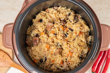 Pilaf with turkey, mutton, beef or pork, carrots, onions, garlic, pepper and raisin in the modern multicooker. A traditional dish of Asian cuisine.