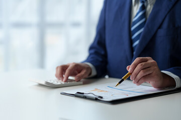 Businessman uses pen to point at chart Graph and use ideas to analyze financial reporting situations. Calculate your investments with the income, tax and accounting calculators at your desk.