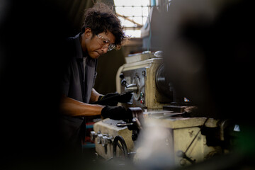 Asian worker in production plant drilling at machine. Professional worker near drilling machine on factory. finishing metal working internal steel surface on lathe grinder machine with flying sparks.