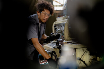 Asian worker in production plant drilling at machine. Professional worker near drilling machine on factory. finishing metal working internal steel surface on lathe grinder machine with flying sparks.