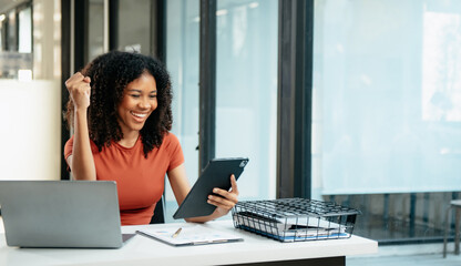 Young woman typing on tablet and laptop while sitting at the working in office