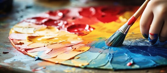 Obraz premium Child's hand dips paint brush into palette, painting on mulberry paper umbrella.