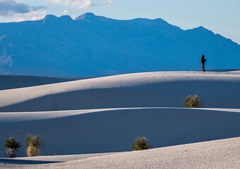 Person walking on White Sand dunes in a distance. Silhouette of man. 