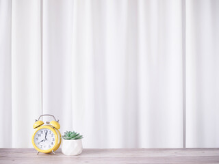 Yellow alarm clock and cactus with white curtain for background. Copy space for text, Office desk...