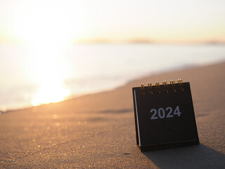 Close up 2024 desk calendar on the beach in the sunset time. Resolution, Goal, Action, Planning,...