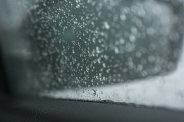 Drops of melted snow - water on the window of a car against the background of an apartment building...