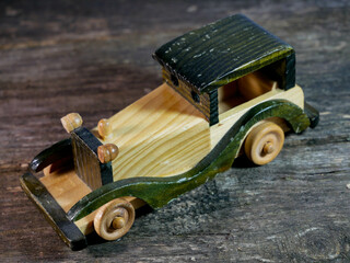 Wooden toy car close up on aged weathered pine wood boards.