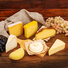 Assorted Italian cheeses on a cutting board on a dark wooden background