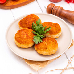 Fish cutlets fried on a plate, lunch, on a light wooden background