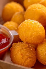 Potato croquettes - mashed potatoes balls breaded and deep fried, served with sauce on a black background.