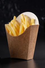 French fries in a paper basket. Fast food.French fries in a paper box on black background