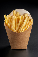 French fries in a paper basket. Fast food.French fries in a paper box on black background