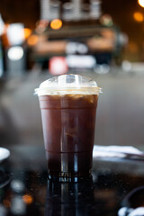 Takeaway plastic cup of iced black coffee or Americano in restaurant.