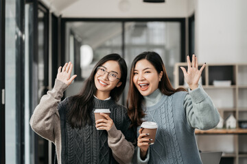 female colleague of half Asian descent holds a cup of coffee and smiles happily.