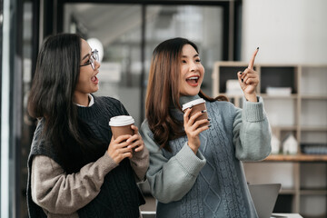 female colleague of half Asian descent holds a cup of coffee and smiles happily.
