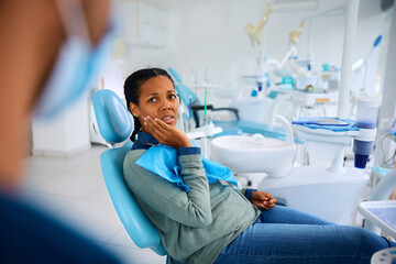 Black woman with toothache at dentist's office.
