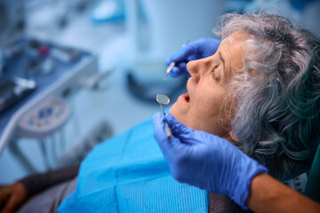 Senior woman getting her teeth examined while visiting her dentist.