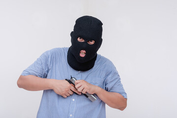 A deranged middle aged man in a black mask. A robber cocking his gun making threatening moves. Isolated on a white backdrop.