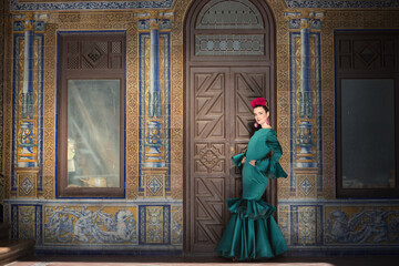 Naklejka premium Young, pretty, blonde woman in typical green colored flamenco suit, posing with beautiful tiled wall in background. Flamenco concept, typical Spanish, Seville, Andalusia.