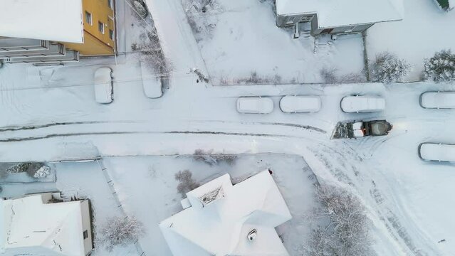 Aerial drone top view of snow plow salt spreader machine cleaning the street in urban aria in the winter season
