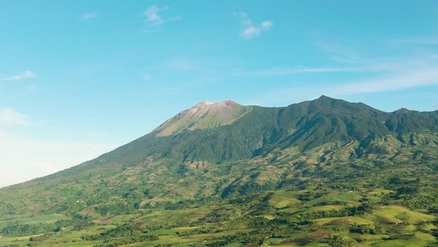 Aerial view of farmland with plantings against a background of mountains and blue sky. Kanlaon volcano. Negros, Philippines