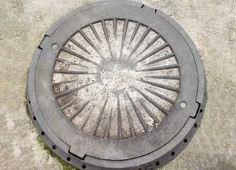 Manhole cover close up picture. Close-up of old metal sewer manhole on a concrete base