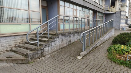 A sloping tile ramp with metal railings was made for people with disabilities in wheelchairs to enter the administrative building. Thus, a barrier-free environment was created. There is a staircase