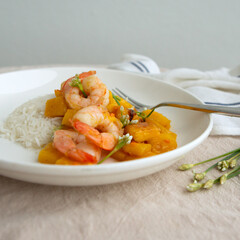 plate with rice and shrimp with mango on a light table