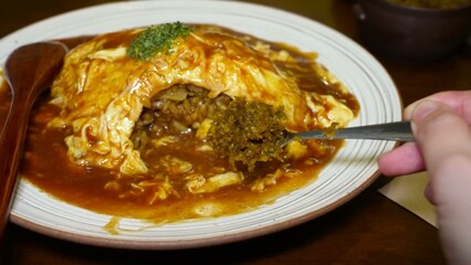 Process of cutting an omelette roll placed on risotto, pouring sauce over the dish