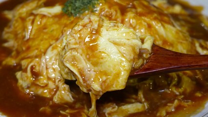 Process of cutting an omelette roll placed on risotto, pouring sauce over the dish