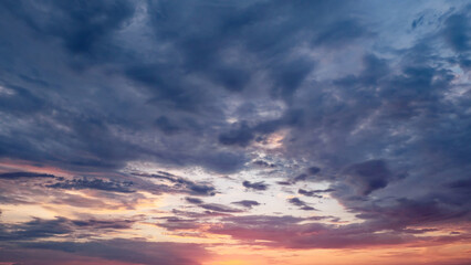 A pink and orange sunset with a cloudy sky, a blue hue, and a purple hue.
