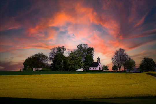 Kleine Kapelle zwischen B&auml;umen mit rotem Himmel