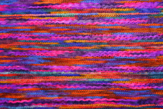 The background is made of a fabric made of natural mixed ethnic wool. Cashmere fabric with multicolored threads. Abstract background, texture. View from above. Flatlay.
