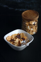 Bowl of cereal, cornflakes with milk in a bowl on a black background