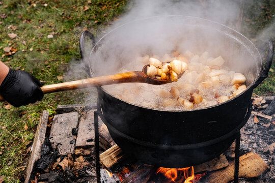 Preparation of delicious unhealthy fried pork greaves in a cauldron on the open fire. Delicious fried pork greaves in the pan traditional Romanian Christmas dish. Crispy deep fried