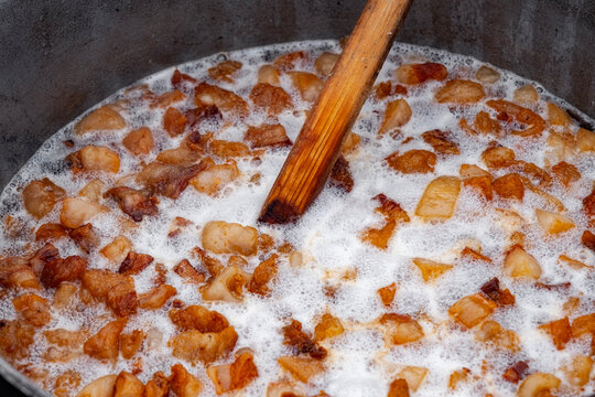Preparation of delicious unhealthy fried pork greaves in a cauldron on the open fire. Delicious fried pork greaves in the pan traditional Romanian Christmas dish. Crispy deep fried