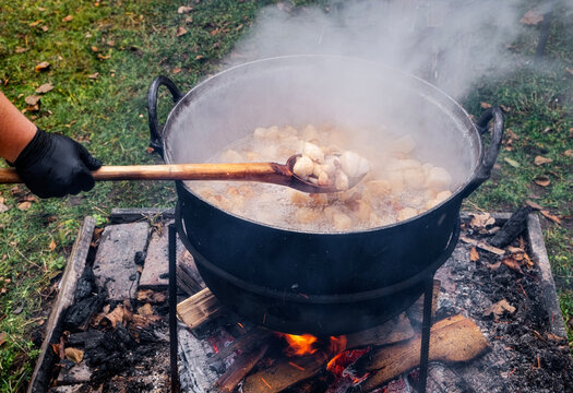Preparation of delicious unhealthy fried pork greaves in a cauldron on the open fire. Delicious fried pork greaves in the pan traditional Romanian Christmas dish. Crispy deep fried