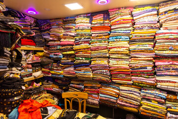 Rolls of fabric and textiles for sale stacked on shelves in shop