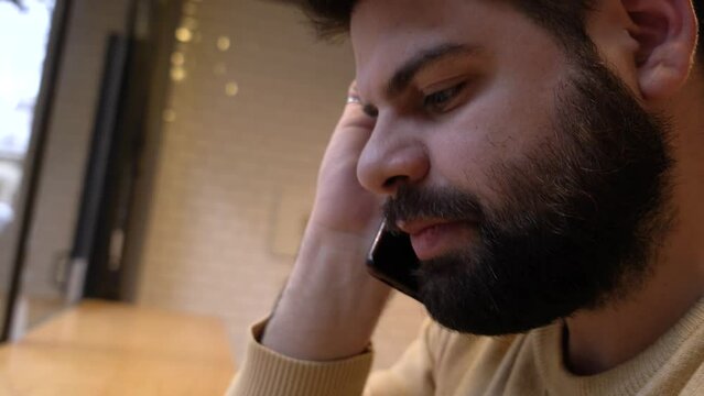 Bearded young guy getting worry by phone call. Close up.