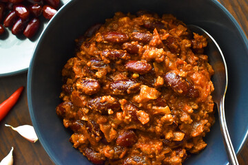 Chilli con carne in a bowl with ground beef,  red kidney beans, onion, chopped tomatoes, cumin, chillies, pepper, paprika and herbs.  Traditional Mexican food. Spicy healthy eating. 