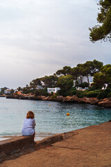 Girl sitting on the beach. View from the back. Place for the text.