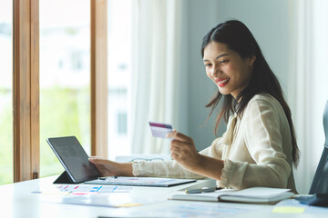 Woman holding credit card and using laptop computer. Online shopping, e-commerce, internet banking concept.