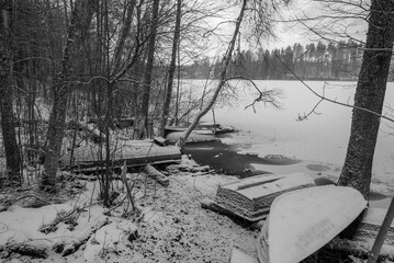 winter landscape with lake shore, flooded boats on lake shore, boat frozen in water