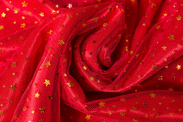 Elegant folded red mesh chiffon fabric decorated with golden stars. Christmas background