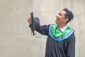 Young Indonesian guys celebration and cheers when graduation moment. The photo is suitable to use for education promotion and academic poster.