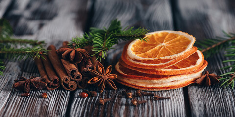 Christmas spices on an old wooden table. Cinnamon, star anise, cloves and dried orange slices. Side...