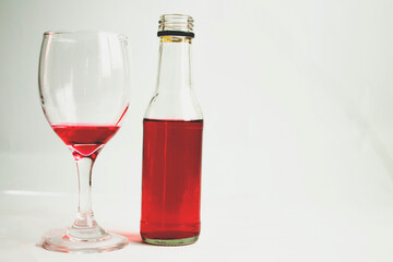 From the picture seen It is a picture of a red wine glass with a red wine bottle next to it. The...