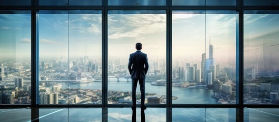 Businessman looking at the city through office window - Powered by Adobe