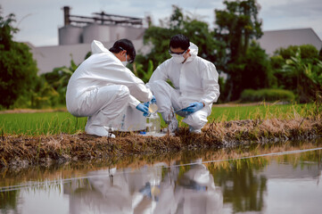 Factory scientists or biologists wear protective clothing while Collecting water samples in natural...